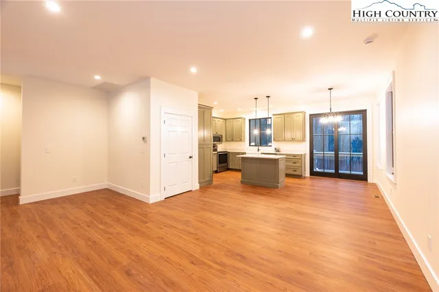 a view of a kitchen with kitchen island wooden floors stainless steel appliances