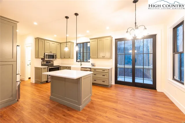 a kitchen with stainless steel appliances a stove a refrigerator a oven and a dining table with wooden floor