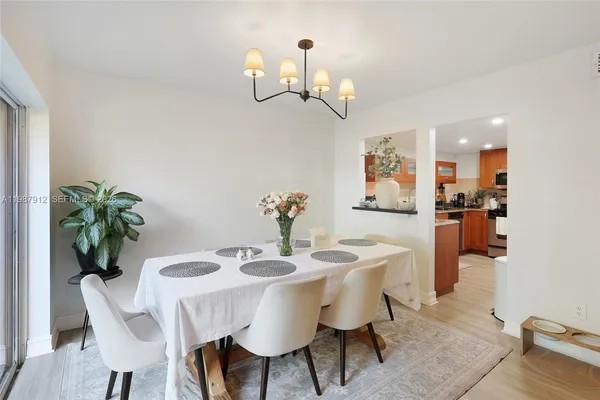 a dining room with wooden floor a chandelier a wooden table and chairs