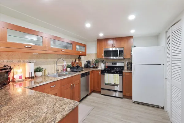 a kitchen with stainless steel appliances granite countertop a refrigerator stove microwave and sink