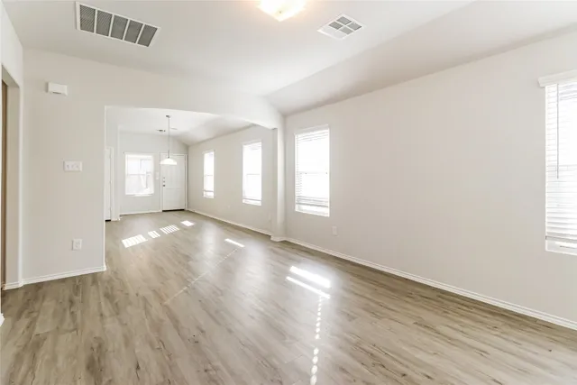 an empty room with wooden floor and windows