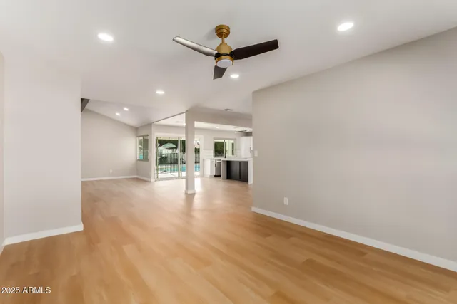 an empty room with wooden floor and ceiling fan
