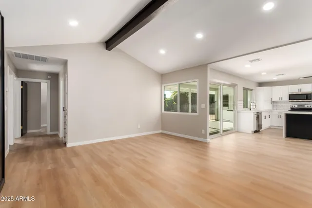 a view of a big room with wooden floor and windows