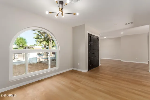 an empty room with wooden floor mirror and windows