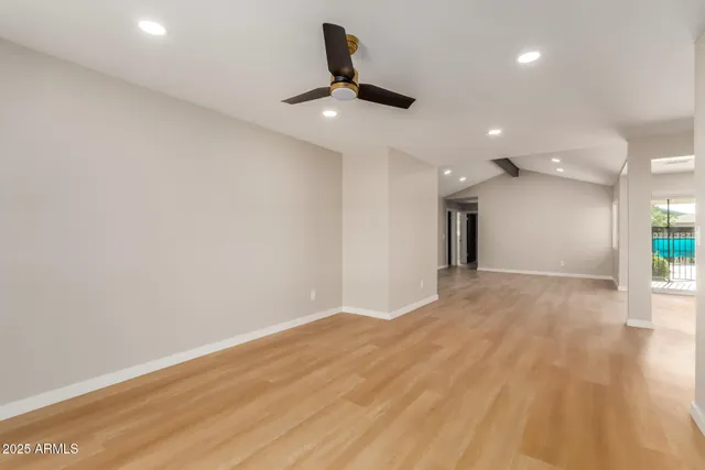 a view of an empty room with wooden floor and a ceiling fan