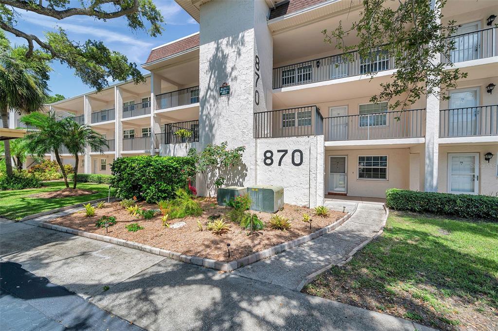 870 Virginia Street, Unit 113 Dunedin, FL 34698 - Photo 1 of 1 a view of a brick building next to a yard