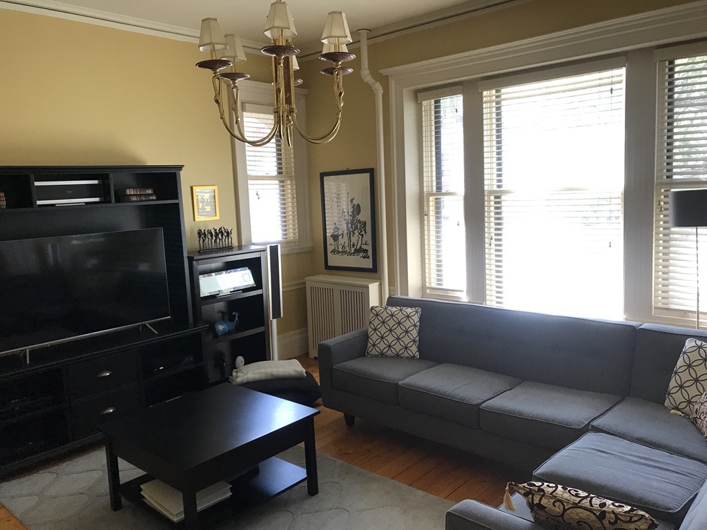 a living room with furniture a flat screen tv and a window