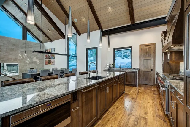 a large kitchen with stainless steel appliances a sink and wooden floor