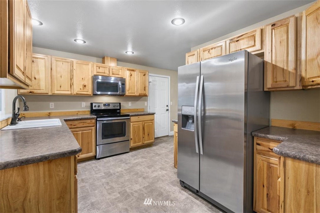 17923 Charlotte Place Southwest Rochester, WA 98579 - Photo 11 of 24 a kitchen with granite countertop a refrigerator a sink a stove top oven and cabinets