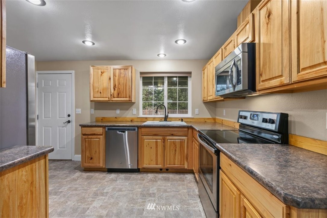 17923 Charlotte Place Southwest Rochester, WA 98579 - Photo 9 of 24 a kitchen with stainless steel appliances granite countertop a stove a sink and a microwave