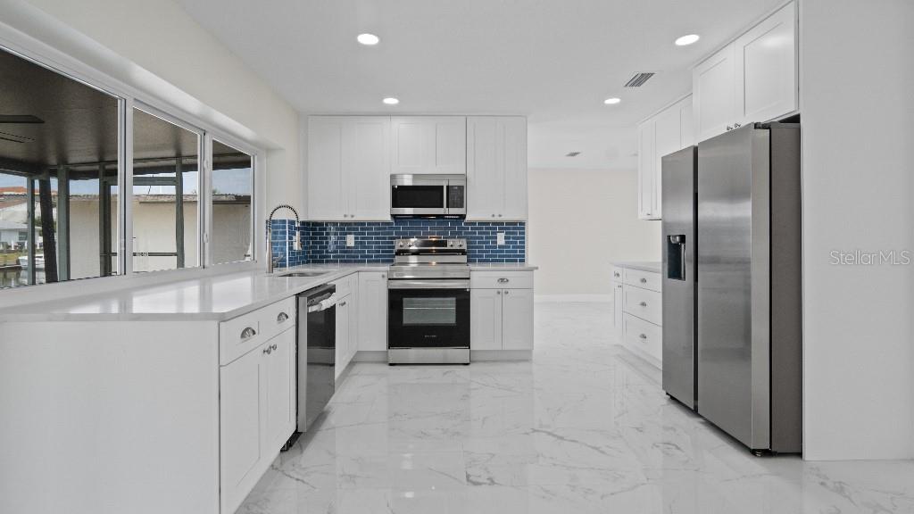 1024 Spindle Palm Way Apollo Beach, FL 33572 - Photo 18 of 50 a large kitchen with stainless steel appliances granite countertop a stove a sink and a refrigerator