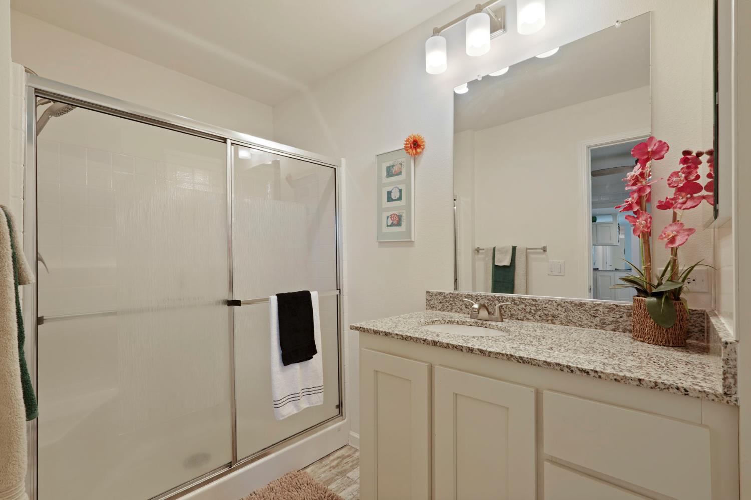 19250 North Lower Sacramento Road, Unit 22 Woodbridge, CA 95258 - Photo 13 of 30 a bathroom with a granite countertop shower sink vanity and mirror