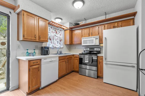 a kitchen with stainless steel appliances granite countertop a refrigerator a sink dishwasher a stove with wooden cabinets and floor