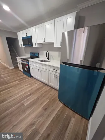 a kitchen with granite countertop a refrigerator sink and white cabinets