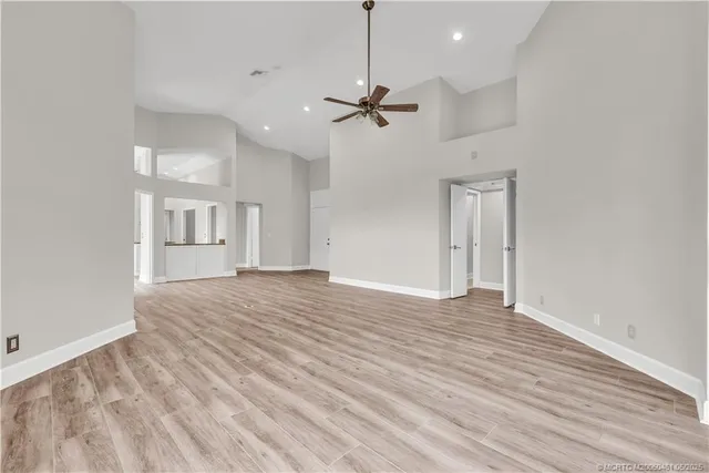 a view of empty room with wooden floor and ceiling fan