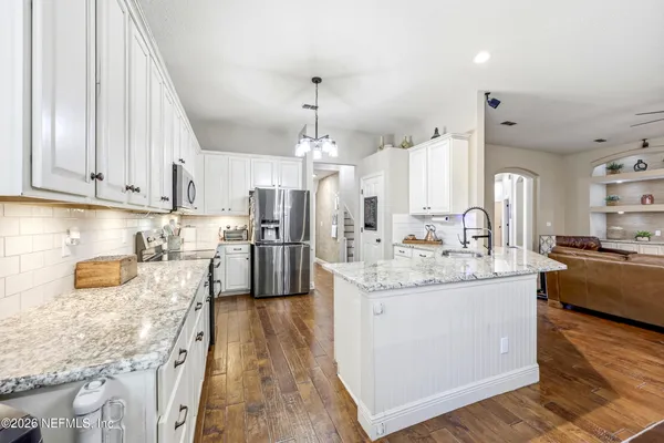 a large kitchen with stainless steel appliances granite countertop a lot of counter space and wooden floor