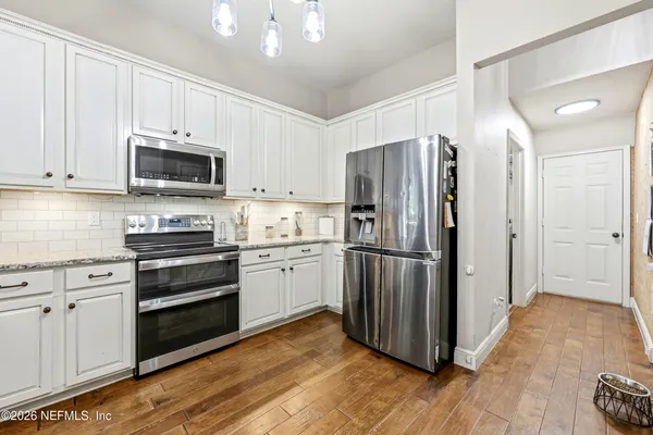 a kitchen with white cabinets and appliances
