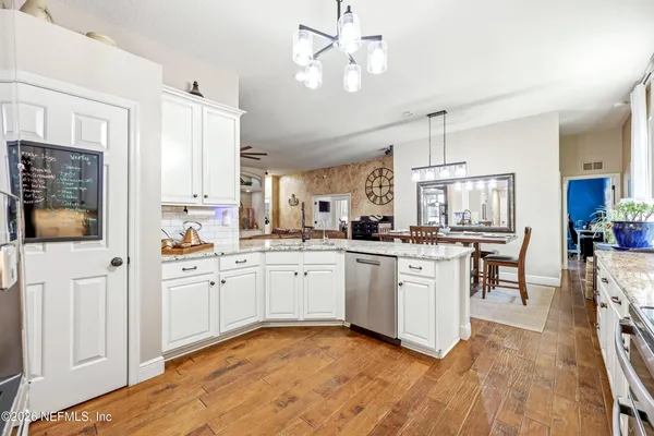 a kitchen with stainless steel appliances granite countertop a stove top oven a refrigerator and white cabinets