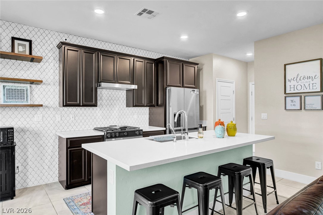 9688 Rankin Rdg Court Las Vegas, NV 89178 - Photo 11 of 53 A contemporary kitchen features dark cabinetry contrasting with a crisp white island and subway tile backsplash.