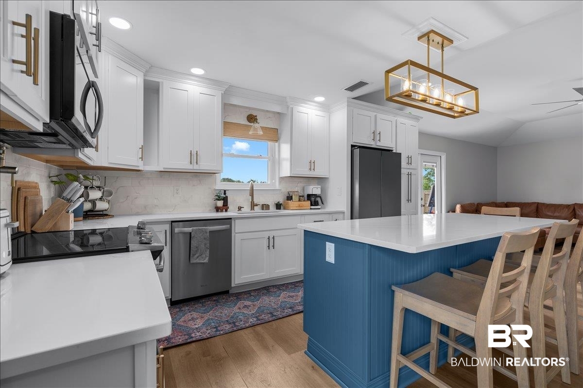 8952 Sherman Road Foley, AL 36535 - Photo 17 of 41 Kitchen featuring a central island with blue beadboard paneling and a light-toned countertop