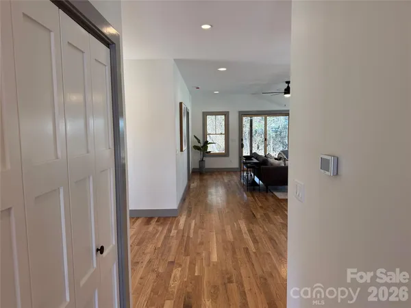 a view of a hallway with wooden floor and a living room