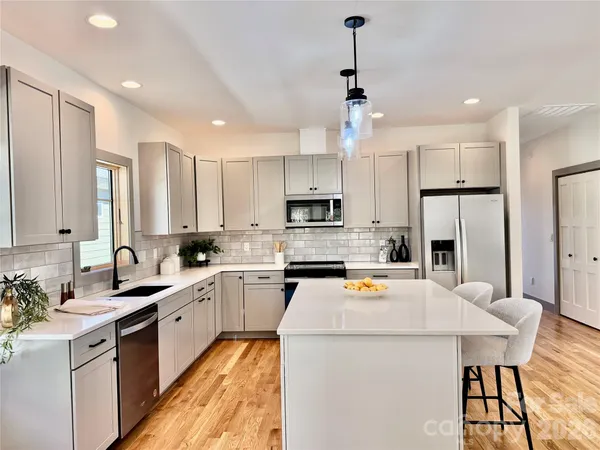 a kitchen with a sink a stove a refrigerator and white cabinets