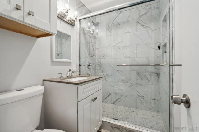 a bathroom with a granite countertop sink a toilet and shower