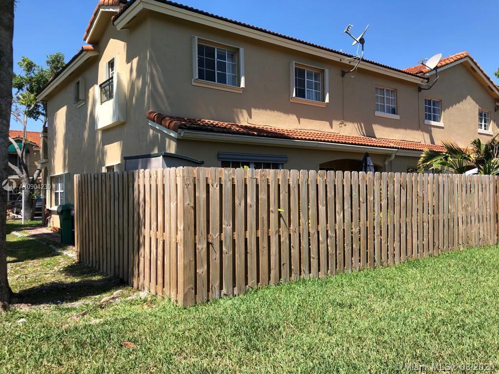 6857 Southwest 158th Pass Miami, FL 33193 - Photo 3 of 41 a back view of a house with a small yard and wooden fence