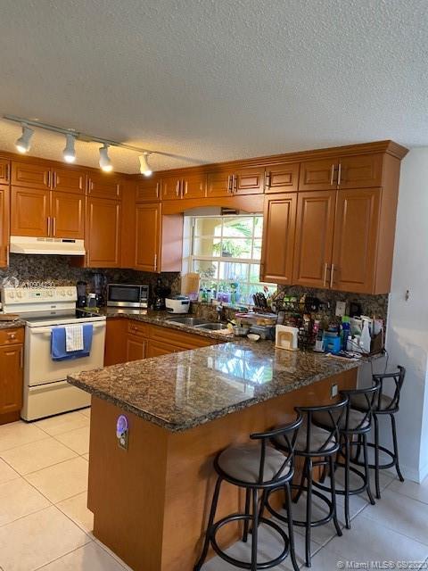 6857 Southwest 158th Pass Miami, FL 33193 - Photo 7 of 41 a kitchen with granite countertop a stove a sink and a wooden cabinets