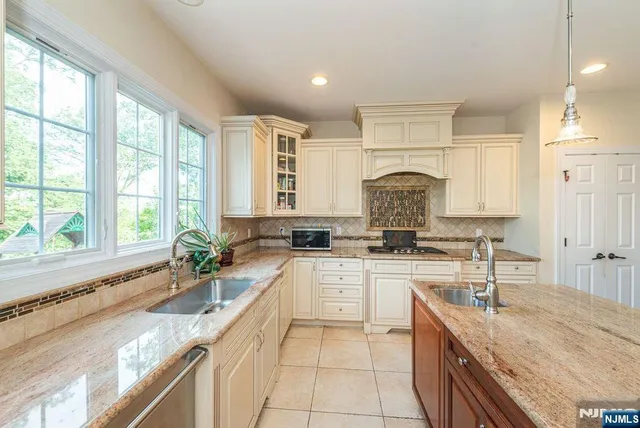 a large kitchen with granite countertop a sink a counter space appliances and a window
