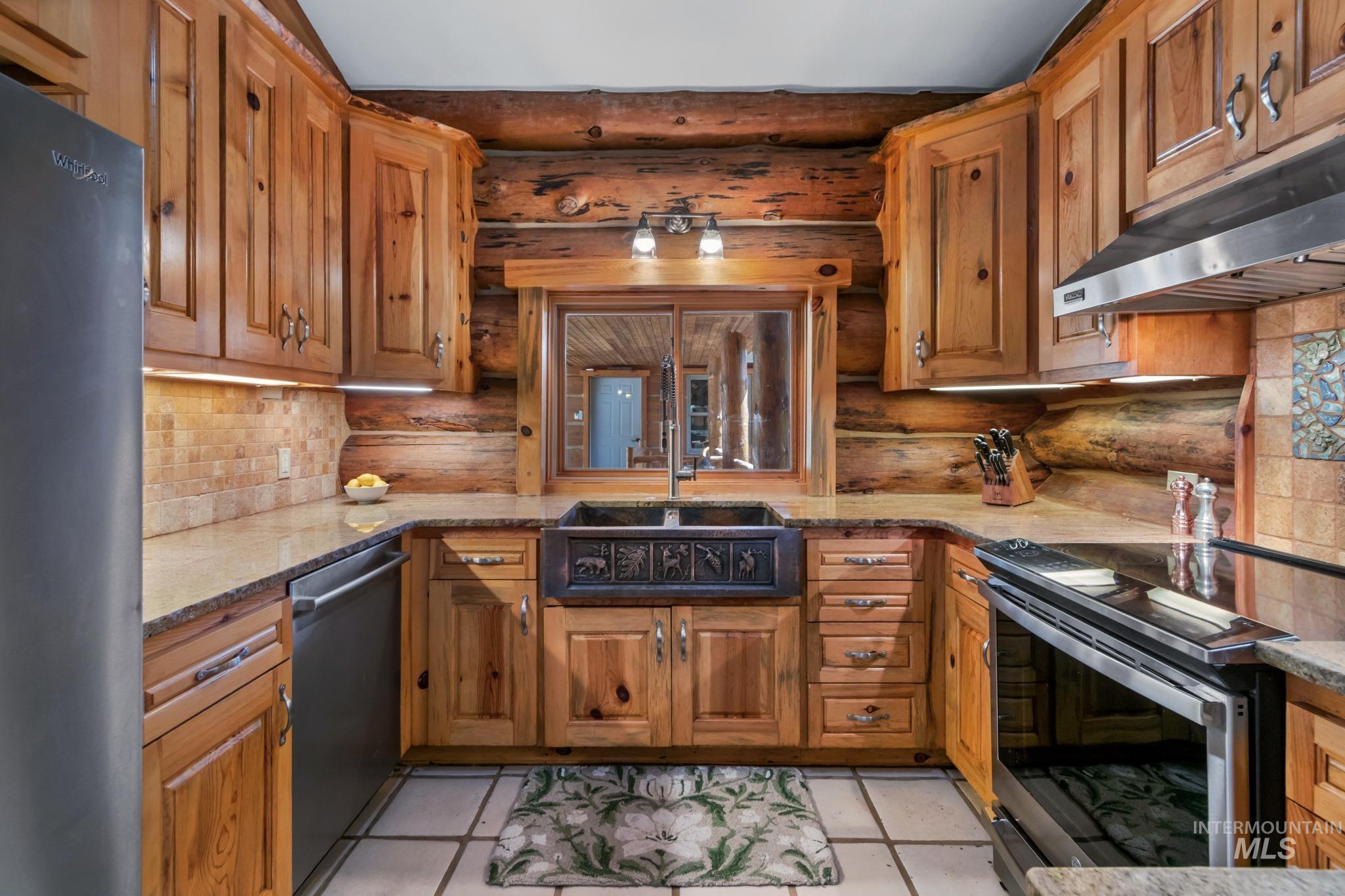 85 Pine Top Road Boise, ID 83716 - Photo 12 of 33 U-shaped kitchen featuring wood cabinetry, light-toned countertops, tile flooring, and a decorative apron-front sink