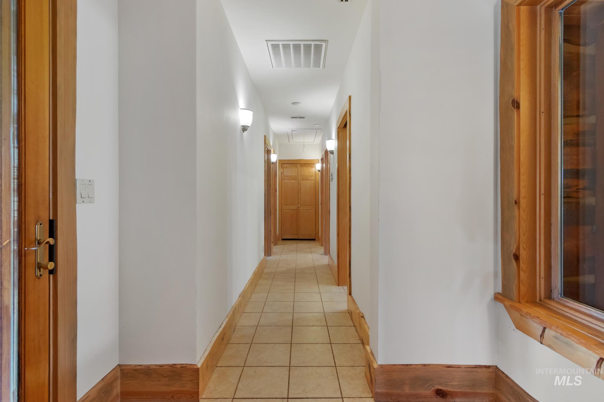 85 Pine Top Road Boise, ID 83716 - Photo 19 of 33 Hallway featuring ceramic tile flooring, wood baseboards, and wall sconces providing illumination