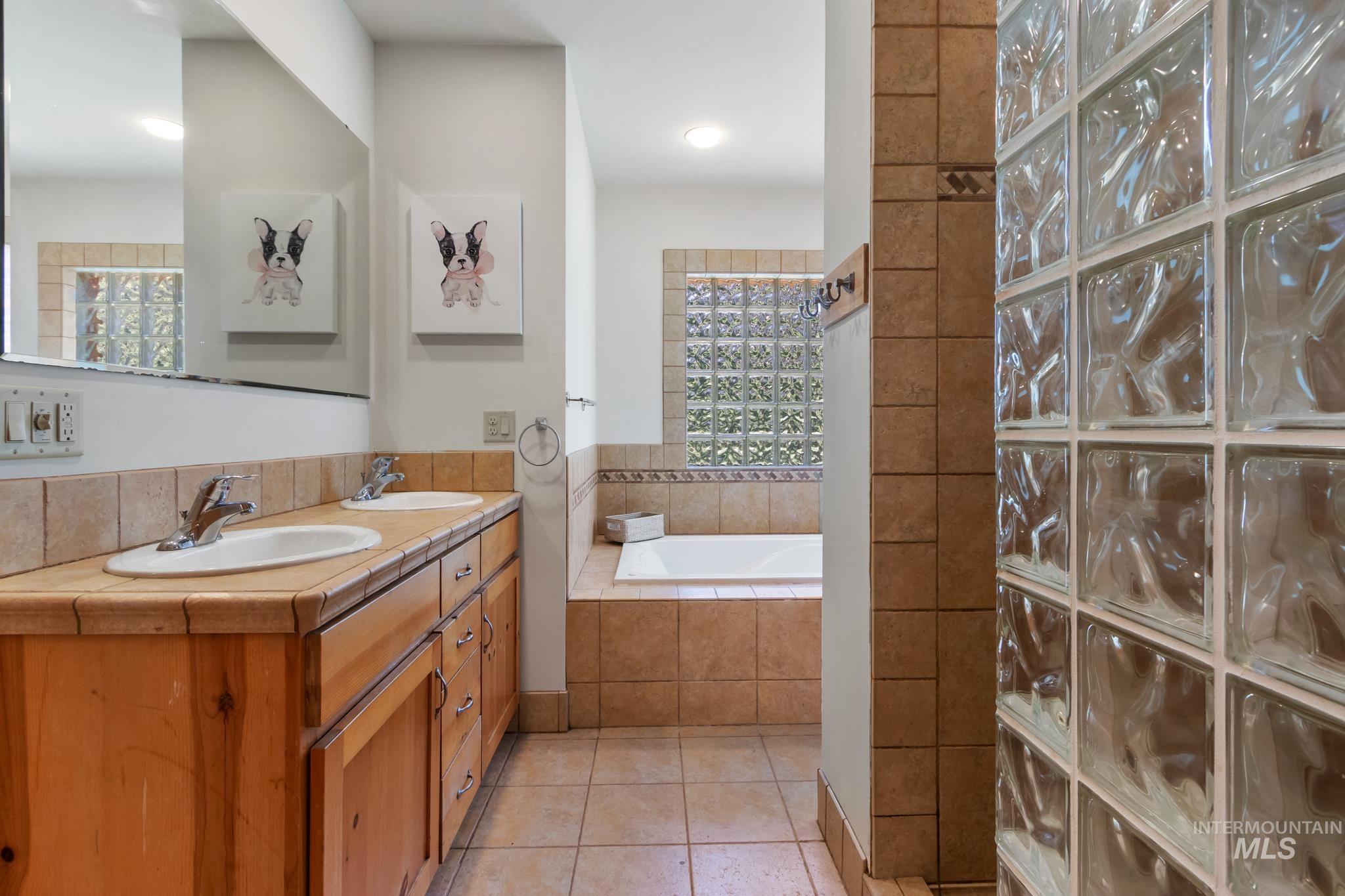 85 Pine Top Road Boise, ID 83716 - Photo 24 of 33 Bathroom featuring a dual vanity with a wood-finish cabinet and tile countertop, a large soaking tub, and glass block window