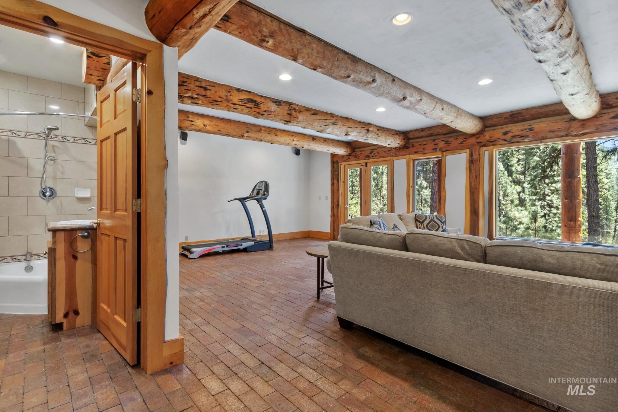 85 Pine Top Road Boise, ID 83716 - Photo 25 of 33 Spacious room featuring exposed log beams, recessed lighting, and brick-finish flooring