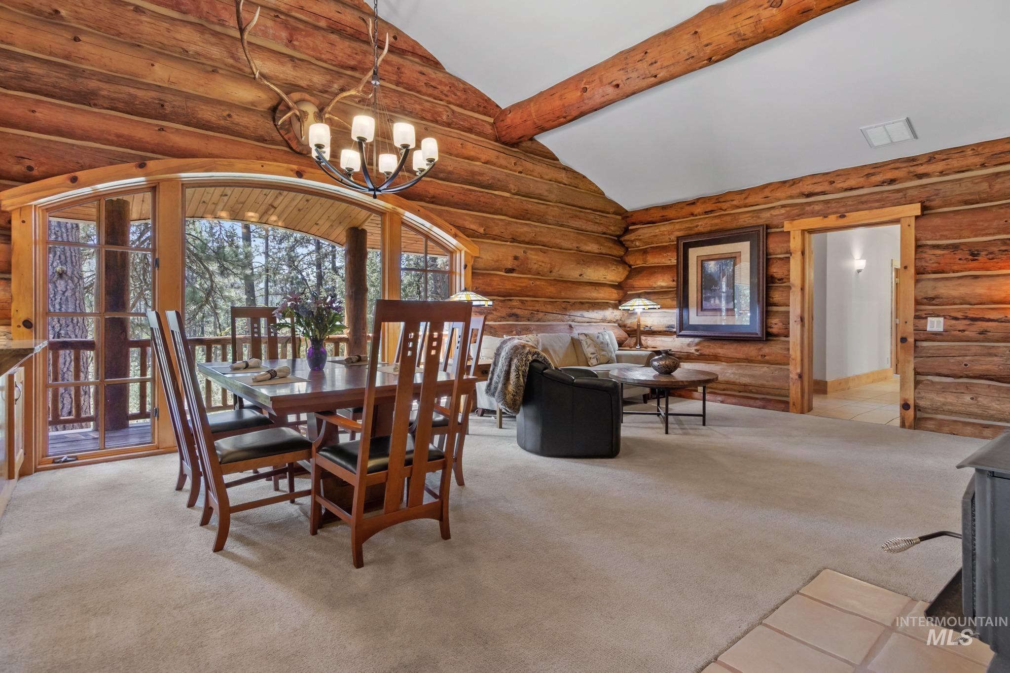 85 Pine Top Road Boise, ID 83716 - Photo 9 of 33 Wood-paneled interior featuring a log beam ceiling, arched window and door frames, and a built-in wall sconce