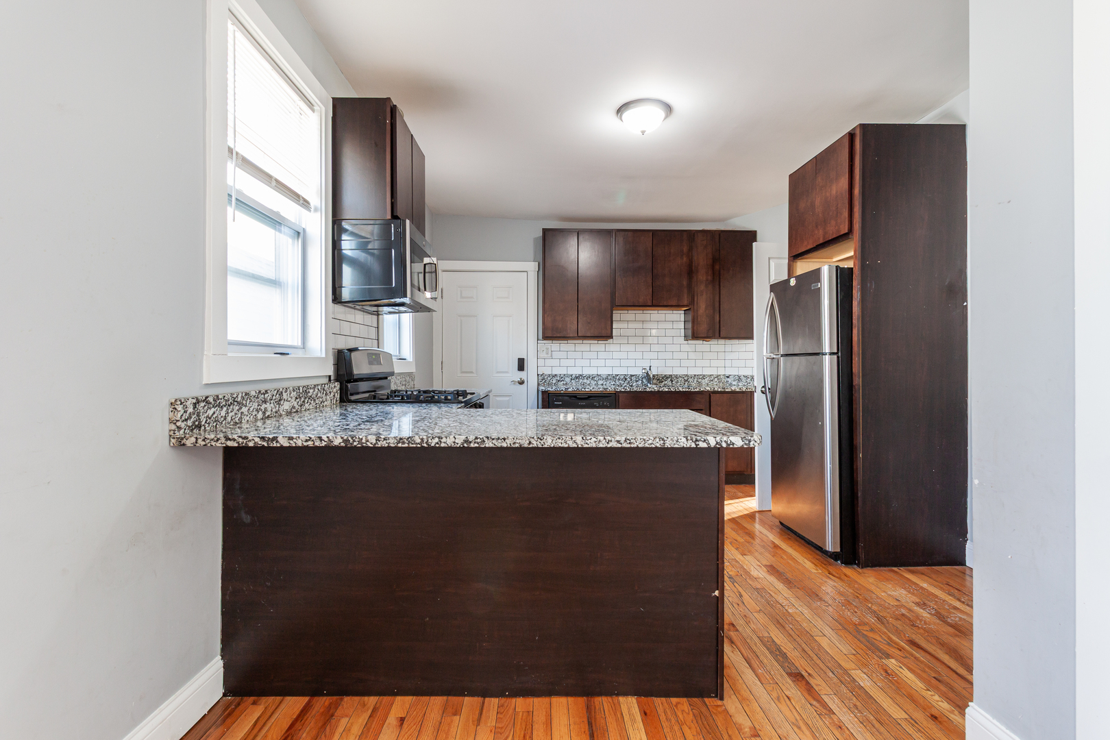 2968 North Ridgeway Avenue, Unit 2R Chicago, IL 60618 - Photo 15 of 23 a kitchen with granite countertop a refrigerator a stove a sink and a window