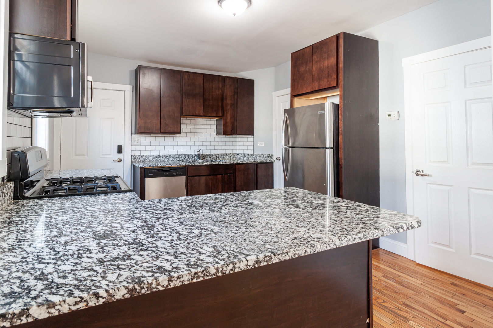 2968 North Ridgeway Avenue, Unit 2R Chicago, IL 60618 - Photo 16 of 23 a kitchen with kitchen island granite countertop a refrigerator and a sink