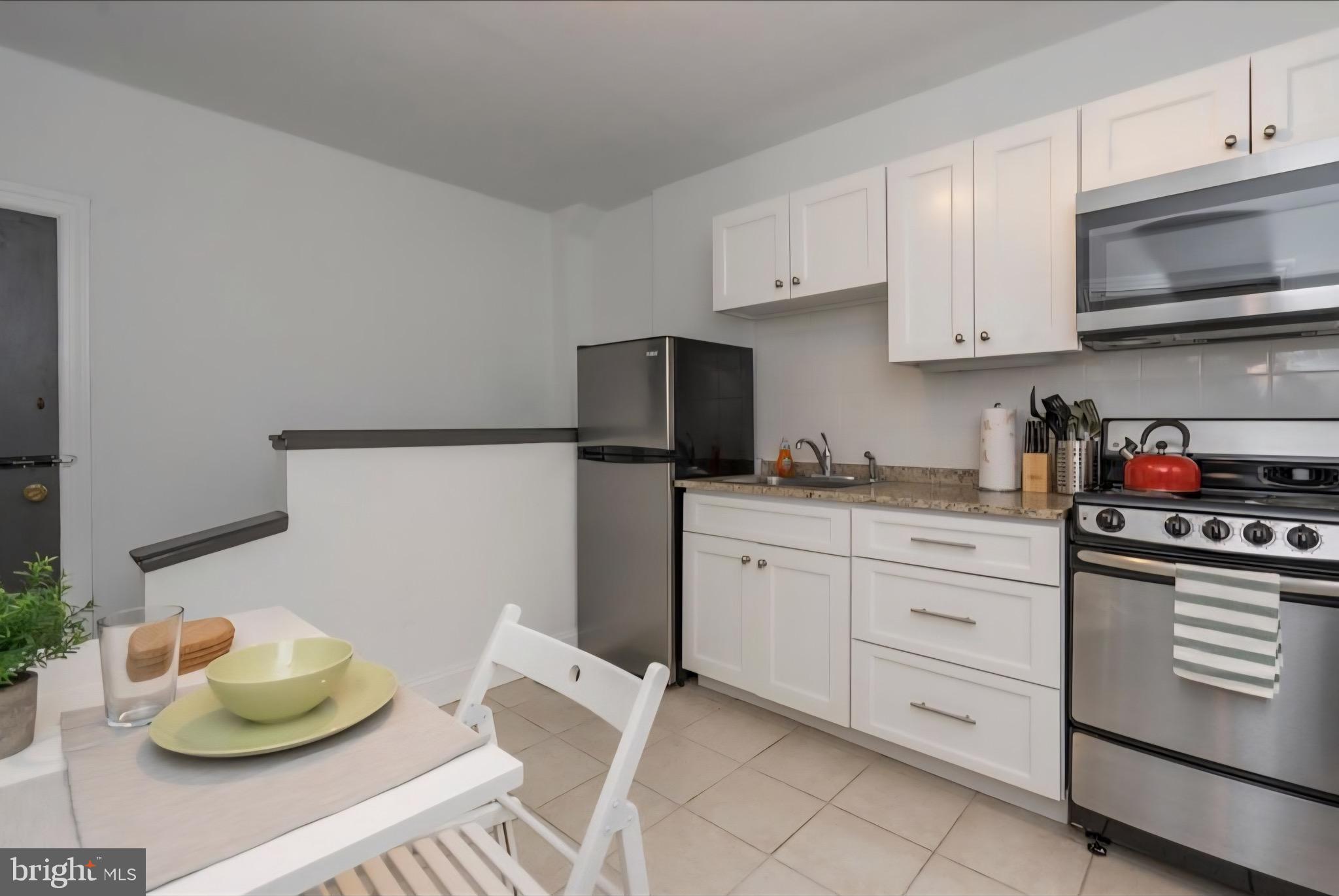 1413 Lombard Street, Unit 2R Philadelphia, PA 19146 - Photo 4 of 15 a kitchen with stainless steel appliances kitchen island granite countertop a sink dishwasher stove and white cabinets