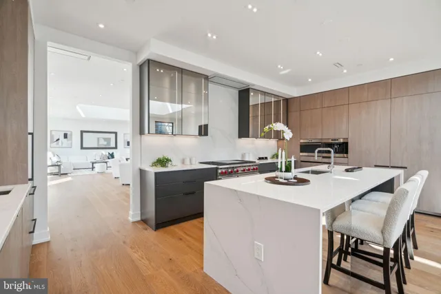 a kitchen with stainless steel appliances granite countertop a stove a sink a refrigerator and chairs