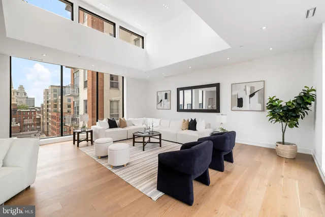 a living room with furniture large windows and wooden floor