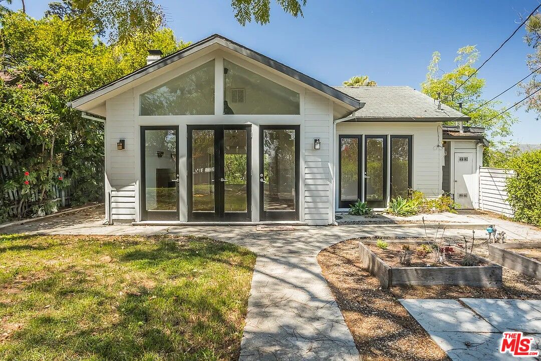 a view of a white house with a large windows and plants