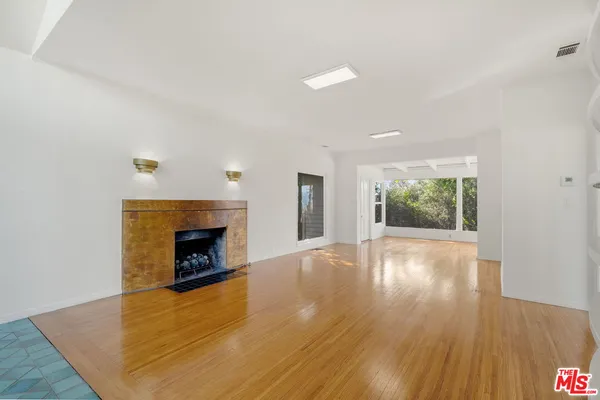a view of an empty room with wooden floor fireplace and a window