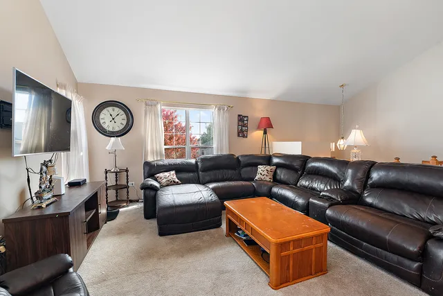 a living room with furniture a clock on wall and a window
