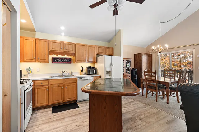 a kitchen with stainless steel appliances granite countertop a refrigerator a stove top oven a sink dishwasher and white cabinets with wooden floor
