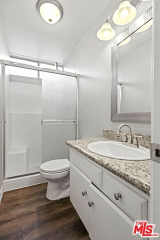 a bathroom with a granite countertop sink toilet a mirror and shower