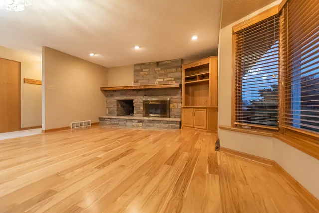 a view of empty room with wooden floor and fireplace