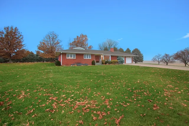 a view of a house with a big yard and large trees