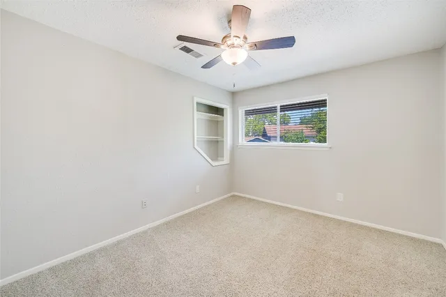an empty room with windows and fan