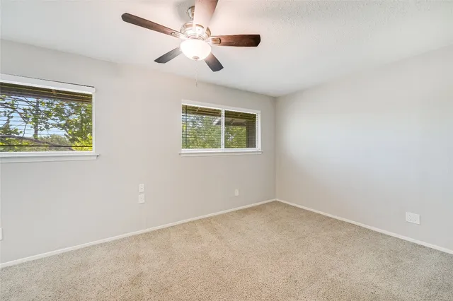 an empty room with a window and a fan