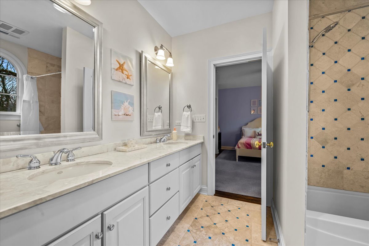 410 Cedar Street Winnetka, IL 60093 - Photo 36 of 57 a en suite bathroom with a double vanity sink a mirror and a bathtub
